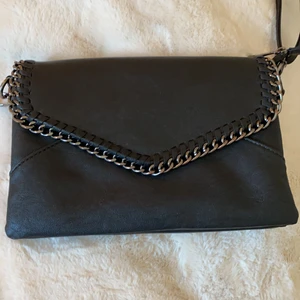 Svart läderväska med coola detaljer! - En svart väska med kedjedetaljer! Kan ha till allt och bara allmänt snygg. Väldigt mycket fickor som är bra så man får ordning i sin väska! Köpt för 600 sek