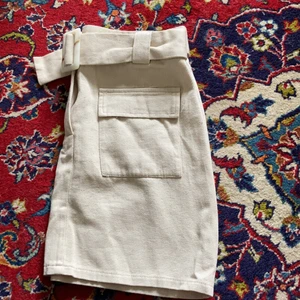 Oanvänd kjol från Nelly - Beige kjol från Nelly, oanvänd med skärp i midjan. 