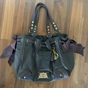 juicy couture väska - En brun juicy couture väska med gulddetajer. I bra skick. Mått cirka 28x38 cm. Skickas med spårbar frakt.