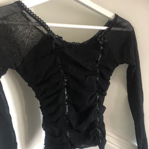 Svart långärmad tröja  - Säljer min svarta långärmade tröja. Den är j genomskinligt material i armarna. Har små rosetter som är jätte fina detaljer. Andvänd några gånger men har i super bra skick.