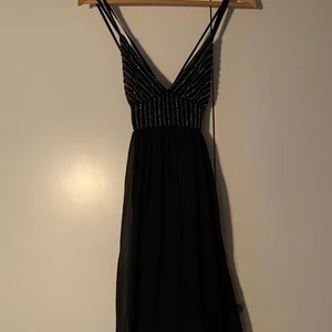 Svart festklänning med paljetter - Snygg svart festklänning med glittriga ”paljetter”. Kjol med fint fall. Märke saknas. Storlek saknas men uppskattas till XS. Materiallapp saknas men chiffon-liknande. Fint skick, jag hittar inga tråddragningar eller paljetter som saknas/är på väg att lossna. Ovanligt för denna slags klänning!