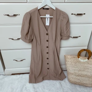 Beige klänning  - Säljer den här beigea klänningen i storlek S. Ny med prislapp. 