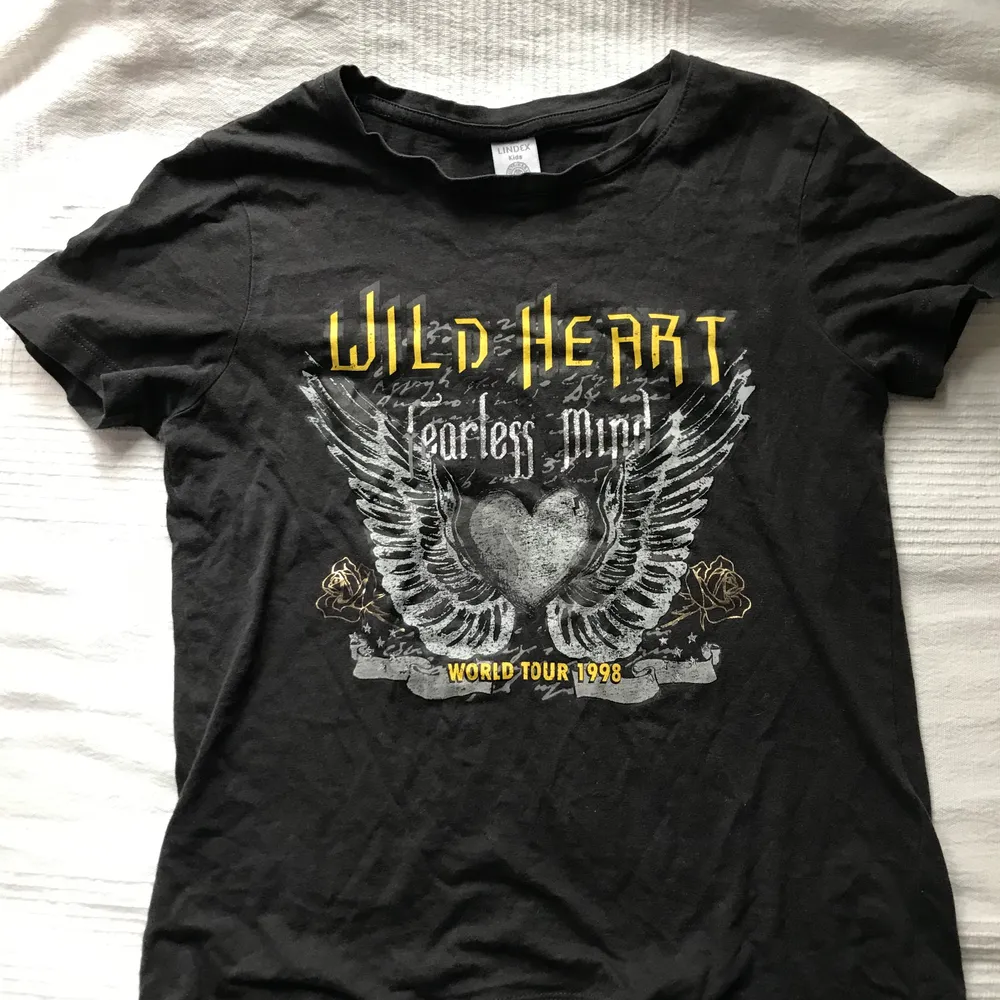 En svart tröja med ett tryck på. Citat: Wild Heart Fearless Mind, World Tour 1998. Hade användt den om den passade i storleken men tyvärr för liten. Inte använd mycket men lite urtvättad så nytt pris!✨. T-shirts.