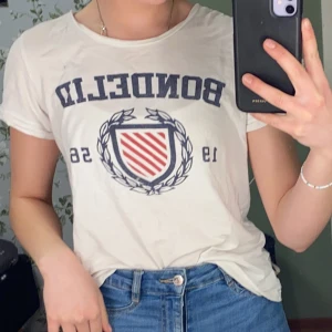 Bondelid t-shirt storlek XS - Vit bondelid t-shirt med blått och rött tryck. Lite urtvättad i färgen. Använd men i bra skick.
