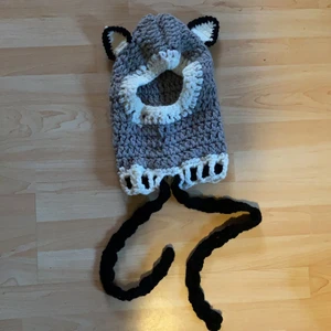 Stickad varginspirerad luva - Helt oanvänd. Detta är en handstickad vargluva med tjockt, behagligt garn. Den har även två svarta band som kan justera spändheten runt nacken.