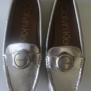 Calvin Klein loafers stl 37,5 nyskick!!! - Snygga loafers i stl 37.5 gulfärgade som passar fint till sommarens solbränna. Sköna och knappt använda då de glappade lite. Om fler är intresserade så buda med 10kr+. Köpare står för spårbar frakt med PostNord 66kr.