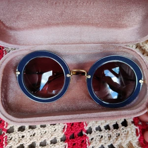 Solglasögon från Miumiu - Solglasögon från Miumiu. Sparsamt använda och inga repor eller dylikt. Dock är plupparna på skalmarna lösa, inget som påverkar funktionen och antagligen lätt fixat hos optiker. Säljs med originalfodral