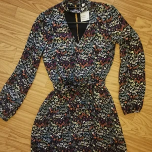 Blommig klänning cut out - Blommig klänning från hm med cut out (blir lite som inbyggd choker) vid halsen och knappar i nacken. Fodrad. Resår i midjan och ett avtagbart knytband med samma tyg. Ny med lappar kvar. Färgen stämmer mest med andra bilden☺️ (lägger all frakt på spårbart, men går ev att få billigare med porto) 