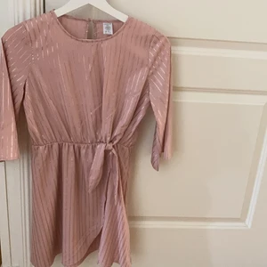 Söt klänning med snöre, fin färg och är till för 9-13 åringar☺️ - Klänningen är rosa och är oanvänd, den har randiga träck med glitter som passar bra med klänningen, klänningen är 5 månader gammal, den passar bra till födelsedagar eller liknandet, materialet är skönt och den är inte så stretchig, värd att prova🥰
