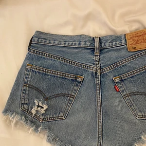 LEVIS SHORTS - LEVIS shorts köpta på second hand. Lite svårt att se storleken men tror det är W30 men passar mig med S och kan förmodligen passa någon som bär strl M. Fransar nertil och det är slitningar på båda bakfickorna ( kan skicka fler bilder på det). Second hand skick💖