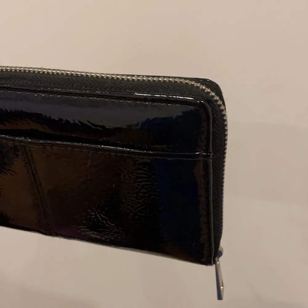 Säljer denna snygga svarta plånbok från Lindex då den inte kommer till användning☺️ Är nästan inte använd alls, den har ett fack med dragkedja i mitten och kortfickor och fickor för kontanter inuti på sidorna. En ficka på framsidan. Jättefin detalj till din outfit🌸. Väskor.