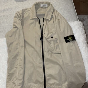 Stone island overshirt - Beige stone island jacka. Säljer den pga inte min stil riktigt. Använd väldigt lite alltså väldigt bra skick. Nypris ca 4000kr och köpt på johnells i Linköping. Strl M.