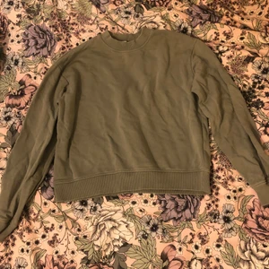 Grön kort sweatshirt i Strl M ✨ - Tröjan är från Na-kd. Den har ett litet tryck med en blomma på ärmen. Nästan nyskick men vet inte vad nypriset är. Den är hyfsat tunn och luftig i materialet! 😇