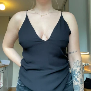 Fin svart topp med detaljer i ryggen - Fintopp från H&M. Djup v-ringning både fram och bak. Fin detalj i ryggen. Strl 36. Använd men ändå i mycket fint skick. 