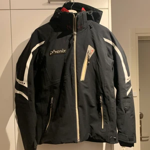 Phenix kvalitetsskidjacka i strl M - Skidjacka från Phenix i storlek M/50. Finns snölås, flertalet fickor inkl för telefon/hörlurar, samt liftkortsficka på armen. Fungerar lika bra i 0 grader som -30 grader. Finns ett lagat hål på framsidan av jackan, men annars i fint skick. Den är några år gammal och nypriset var mellan 6000-7000kr.