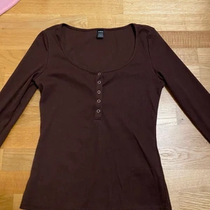 Brun tröja - Fin brun tröja med knappar man kan öppna vid bysten. Jag har aldrig använt den för armarna är för korta på mig och lite för kort vid magen i min smak annars bra material och fin tröja överlag. Fraktar ej men möts up 😊