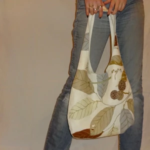 Handgjord tygväska/tygpåse mönstrad brun - Tygväska / tygpåse i modellen Frida som går att vända ut och in, en sida mönstrad och en sida i linne med applikation, samt dragkedjsficka. Perfekt till skola eller som vardags väska  Pris: 200kr Frakt: gratis 