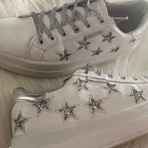 Sneakers med stjärnor  - Super snygga sneakers med silvriga stjärnor! Skosnörena är också i glitter silver. Använda några gånger! (Lånad bild) skriv för fler bilder! 