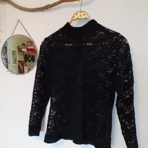 Svart spetströja - Spetströja från HM. Perfekt att ha under för att visa upp sin snygga t-shirt, men funkar också bra själv t.e.x vid fest. Tröjan har en polokrage, och i nacken finns en liten dragkedja för kragen (bild skickas vid förfrågan). Storleken är L men den funkar även för M