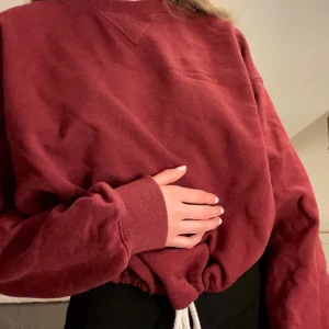 Vinröd hoodie strl XS - En hoodie köpt från BIK Bok för 300 kr. Hoodien är knappt använd och är därför i nyskick. Säljer för att den just aldrig kommit till användning. Den har en knytbar resår i midjan så att du själv kan välja hur den ska sitta. Såhär sitter XS på mig som är drygt 170 cm. 