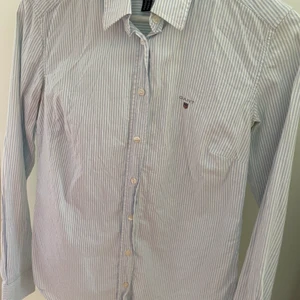 Gant skjorta Dam - Gant dam skjorta i storlek 36. Blå vit randig. Lite missfärgad under armhålan. Ord pris 1200 kr