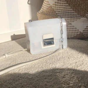 Väska  - Hård plast. En aning genomskinlig. Passar till allt. 