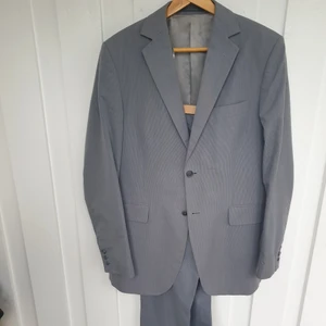 Tigerkostym (herrmodell) säljes - Herrkostym av märket Tiger (of Sweden) säljes.  Grå smalrandig, i fodret på kavajen finns Tigers logotyp, hög kvalitet. Nyskick, knappt använd.   Mått: Kavaj: axelbredd 45,  ärm 65,  längd(baksöm) 85.  Byxa: midja 85,  längd 104.  Passar bra för en person ca 185cm lång.