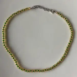 Underbart halsband med guldiga och gröna detaljer! Justerbart med kedja, passar alla! 