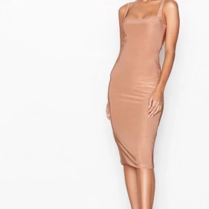 Klänning Nelly - Klänning från Nelly som aldrig använts. Lapparna sitter kvar. Den är i midi långt, exakt som den sitter på modellen. Jättefin beige färg med lite glans. 