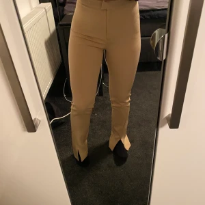 Kostymbyxor från nakd  - Beiga kostymbyxor från nakd med slits längst ner. Storlek 34 men passar även 36. 