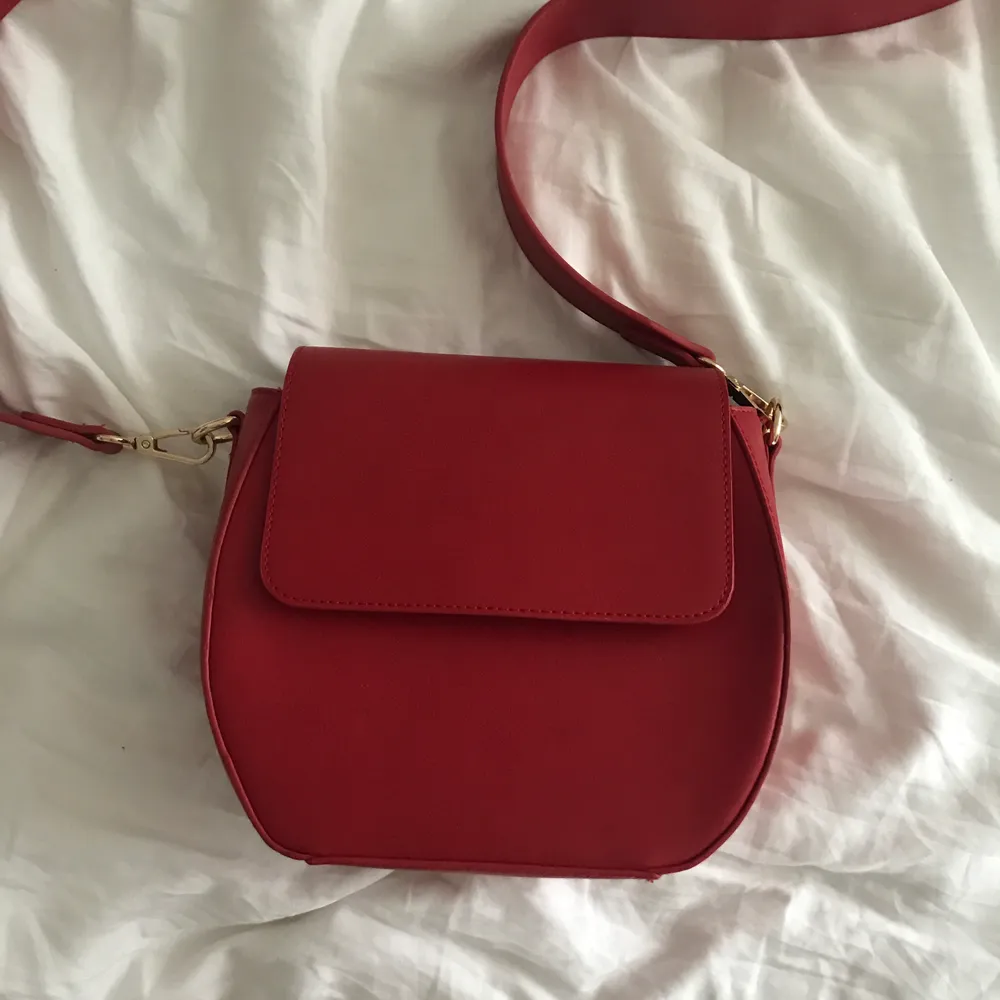 Röd crossbodybag från ASOS! Perfekt storlek som rymmer mycket. En mindre ficka inuti också. . Väskor.