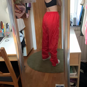 Umbro ”windbreakerpants” - Feta röda Umbro ”windbreaker” byxor, strlk L men finns band som går att dra åt i midjan så de passar andra storlekar  (jag är 36/38). (Jackan som hör till finns i en annan annons).