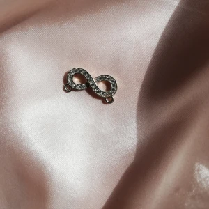 Berlock  - Superfin berlock i form av ett evighetstecken dekorerat med kristaller.