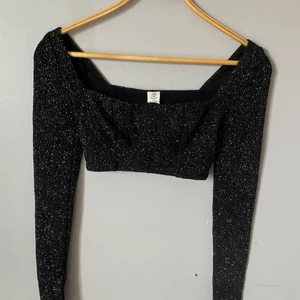 Glittrig topp - En svart, glittrig topp från Urban Outfitters! Den har bröstutfyllnad