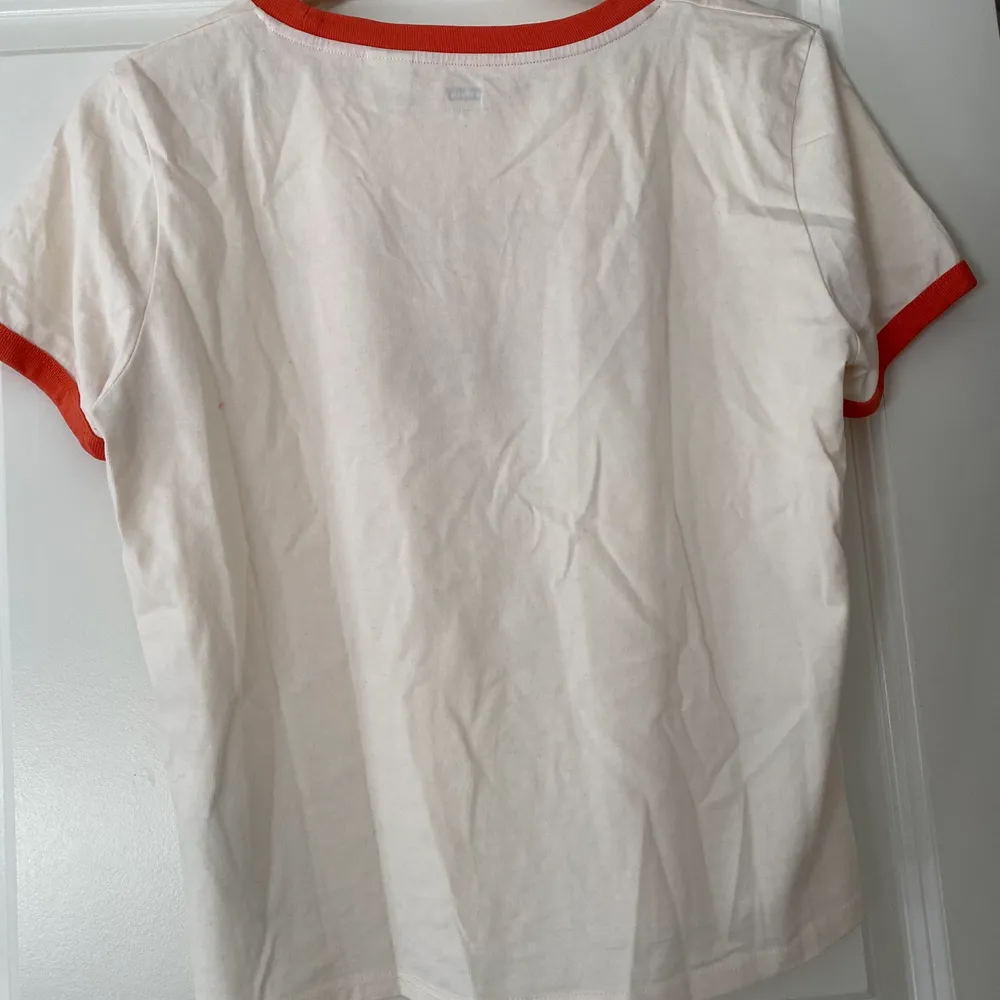 En vit Levis tröja med orangea detaljer. Begagnat skick. Frakten är inte inkluderad i priset då jag inte vet helt 100 vad den blir. Köparen står för frakt.  Allt som säljs kommer från ett rent djur- och rökfritt hem.. T-shirts.