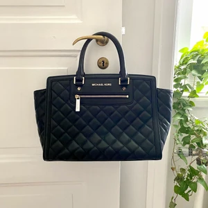 Michael Kors Selma väska - Väska från Michael Kors i modellen Selma Quilted Black Leather. Mjukare och finare i lädret än den vanliga Selma modellen i saffiano läder. Inga fläckar på utsida eller insida, knappt använd. Enda tecknet på användning är metallfötterna (se bild). Axelrem och dustbag medföljer.  Nypris ca 3500kr 
