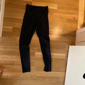 ”Grease byxor” stl S stretch  - Glansiga svarta byxor från Divided H&M. Ej skinnimmitation utan något glasigt tyg. Väldigt stretchiga över rumpa/lår. 