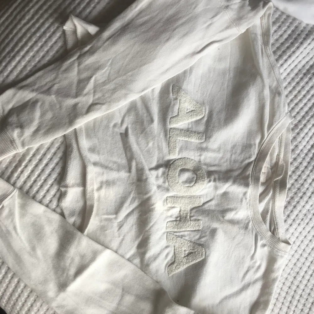 En vit långärmad croppad tröja med diskret text på. Är i storlek S men passar både XS och M med.. Toppar.