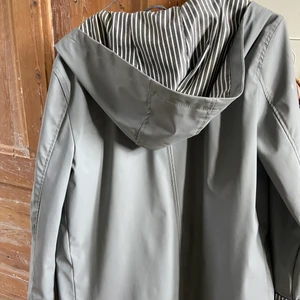 Regnkappa - Grå regnkappa med randiga detaljer. Sitter som en S.