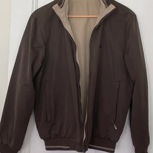 Jacka 2 i 1 - Vändbar vårjacka – en brun och en beige sida - kan användas även som höstjacka från franska märket JEREM. Jackan stängs med dragkedja. Jackan går att vända ut och in och har två sidfickor - oavsett sida.   2 jackor i 1 helt enkelt