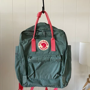 Fjällräven kånken Frost green-Peach - Nypris 999kr, är i använt skick, har några fläckar. Everyday outdoor Kånken. Mått: Höjd: 38cm, Bredd: 27cm, Djup: 13cm, Volym: 16 l, Laptopfack: Ja, Vikt: 300g 