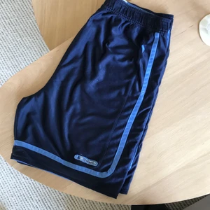 Wilson vändbara basketshorts - Vändbara basketshorts från wilson i storlek XL, man kan ha dem mörkblå med ljusblå rand eller ljusblå med vit rand. De är väl använda och har rätt mycket noppror och små hål - därav priset.