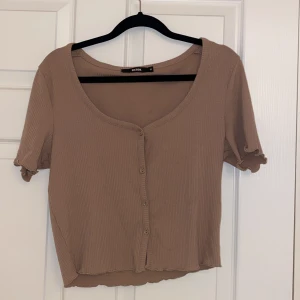 Beige topp med knappar  - En beige topp, mellan lång 