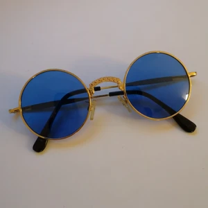Solglasögon  - Coola retro style solglasögon i guld och blå. Ca 13 cm breda. Glaset är 4,5x5cm. Kan skicka som brev för 15kr. 