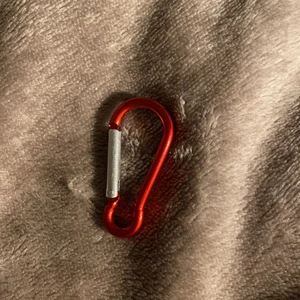 En klämma/hängare - Funkar till väskan, hänga upp saker mer och annat. Ungefär 3cm lång. 1cm bred
