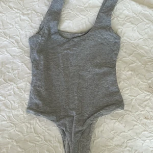 Grå body från Meshki - Säljer denna snygga gråa body i galet skönt material då den är för liten för mig. Den är sparsamt använd. Köparen står för frakten vilket brukar bli runt 48 kr, har du några frågor så tveka inte på att skriva till mig! 😊