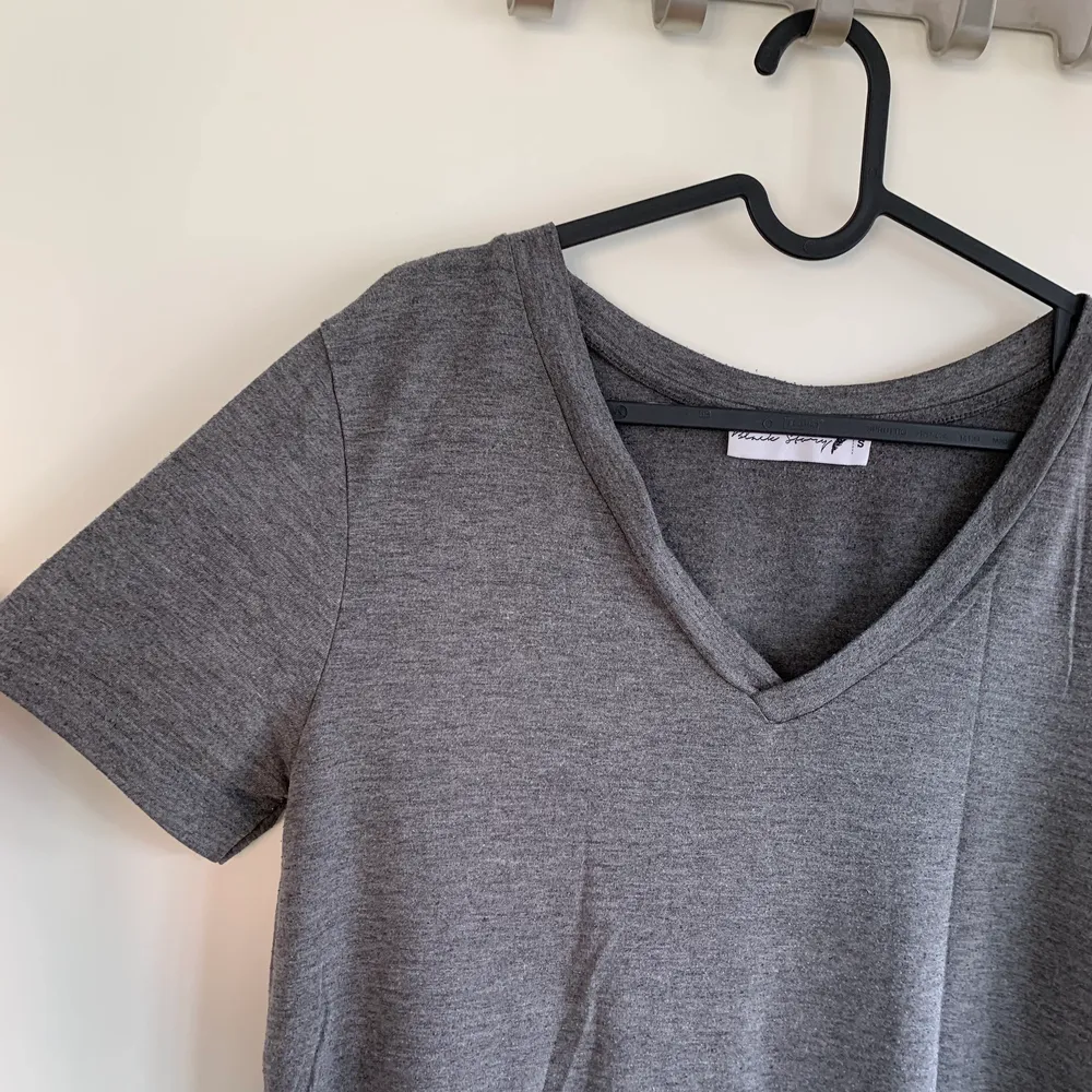 En grå V-ringad T-shirt med tunnare tyg. Ganska stor i modellen och passar upp till L skulle jag säga. Använd men som i nyskick. . T-shirts.