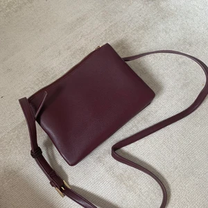 Crossbody bag - Mörkröd axelbandsväska från Forever 21. Väskan har 3 separata fack som alla har dragkedja. I väldigt bra skick. Bandet går att justera till olika längder. Så fin väska till hösten. Jag har en liknande så får tyvärr ingen användning för denna.