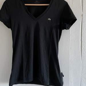 En svart t-shirt från Lacoste. Den har ett litet hål på framsidan som knappt syns, annars bra skick. 