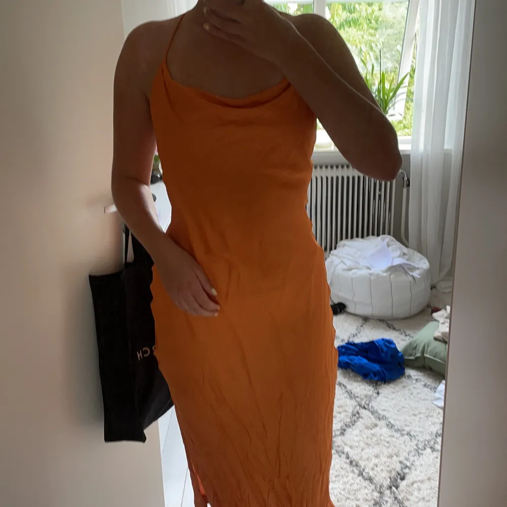 Knälång klänning i jättefin orange färg med knytning i ryggen och slits på vänster sida . Klänningar.